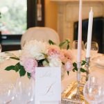 A beautifully decorated wedding table with pink flowers, candles, and an elegant card.